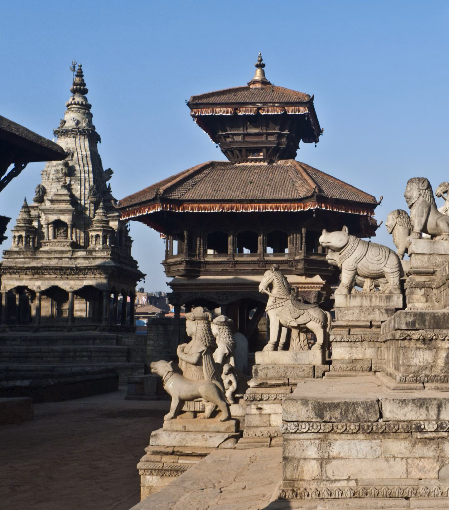 Stone animal statues with Patan Durbar Square temples in the background