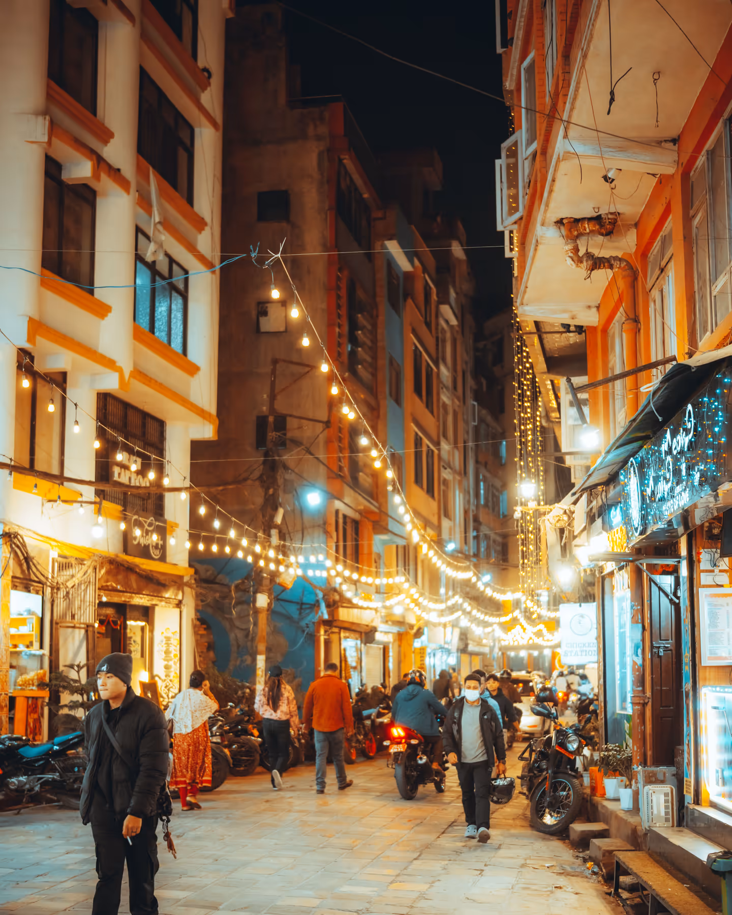 People walking at night through a lit-up Kathmandu street