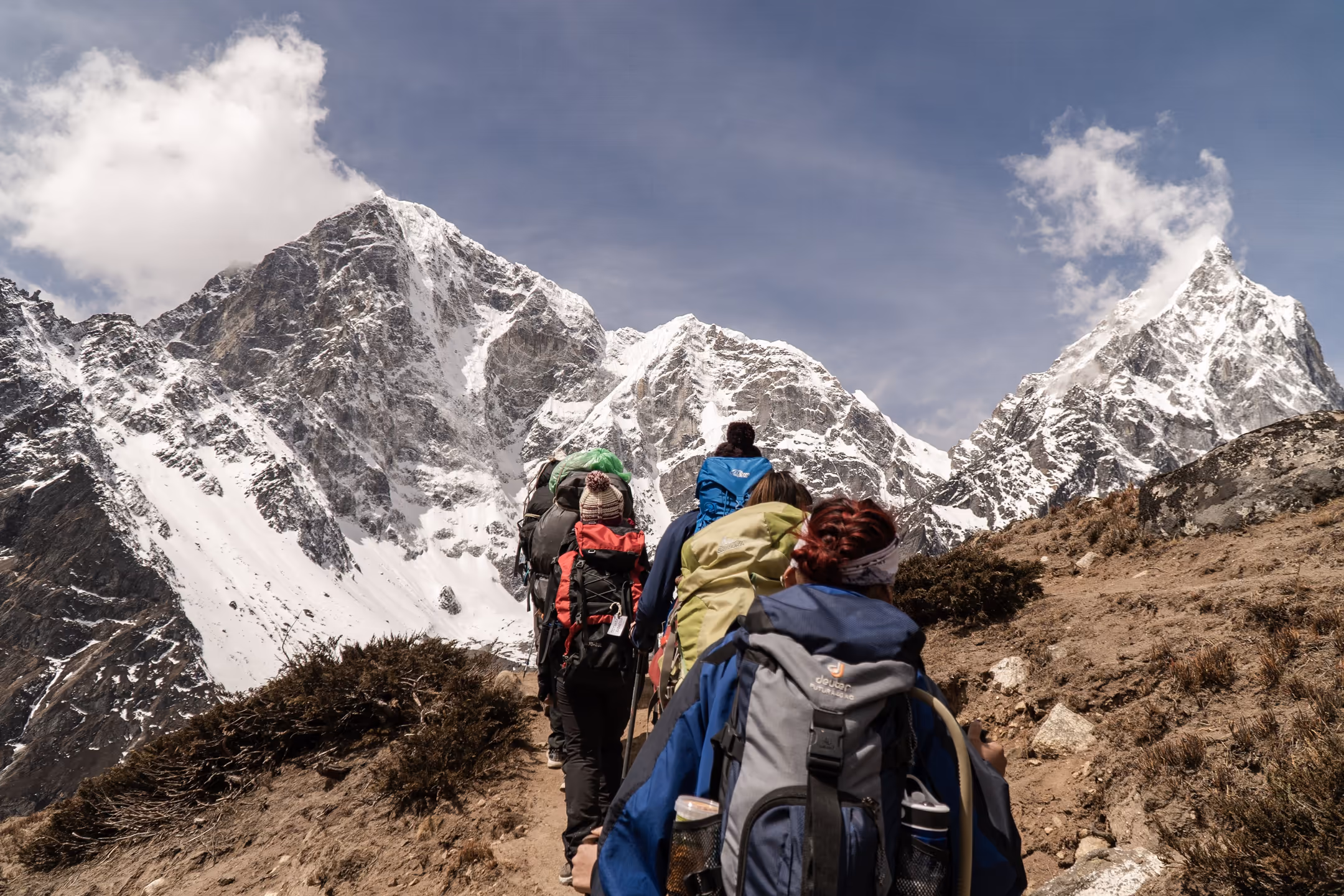 Trekkers walking along a well-marked trail with a dramatic Himalayan mountain backdrop