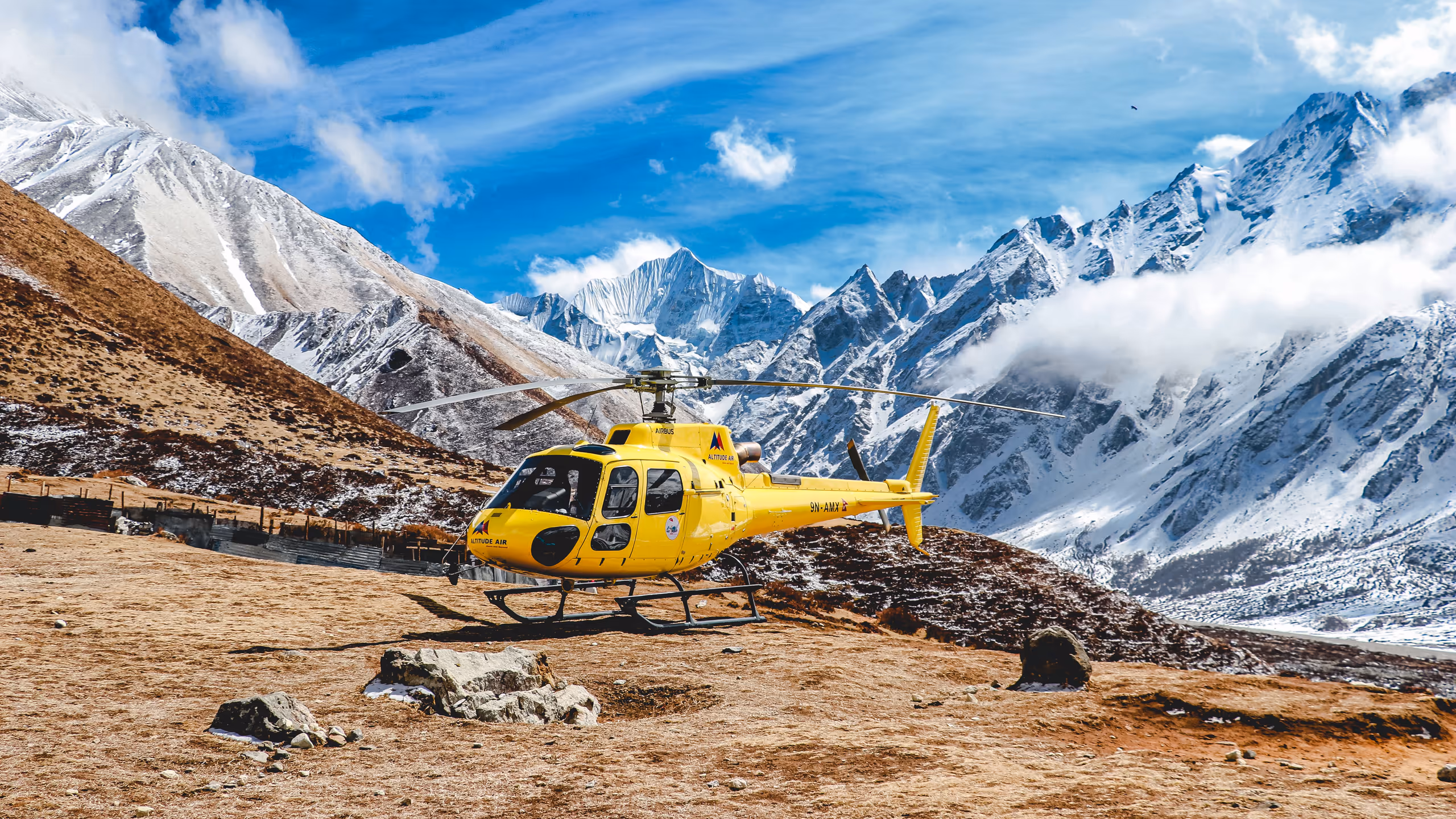 Yellow helicopter parked in a snow-covered mountain basin